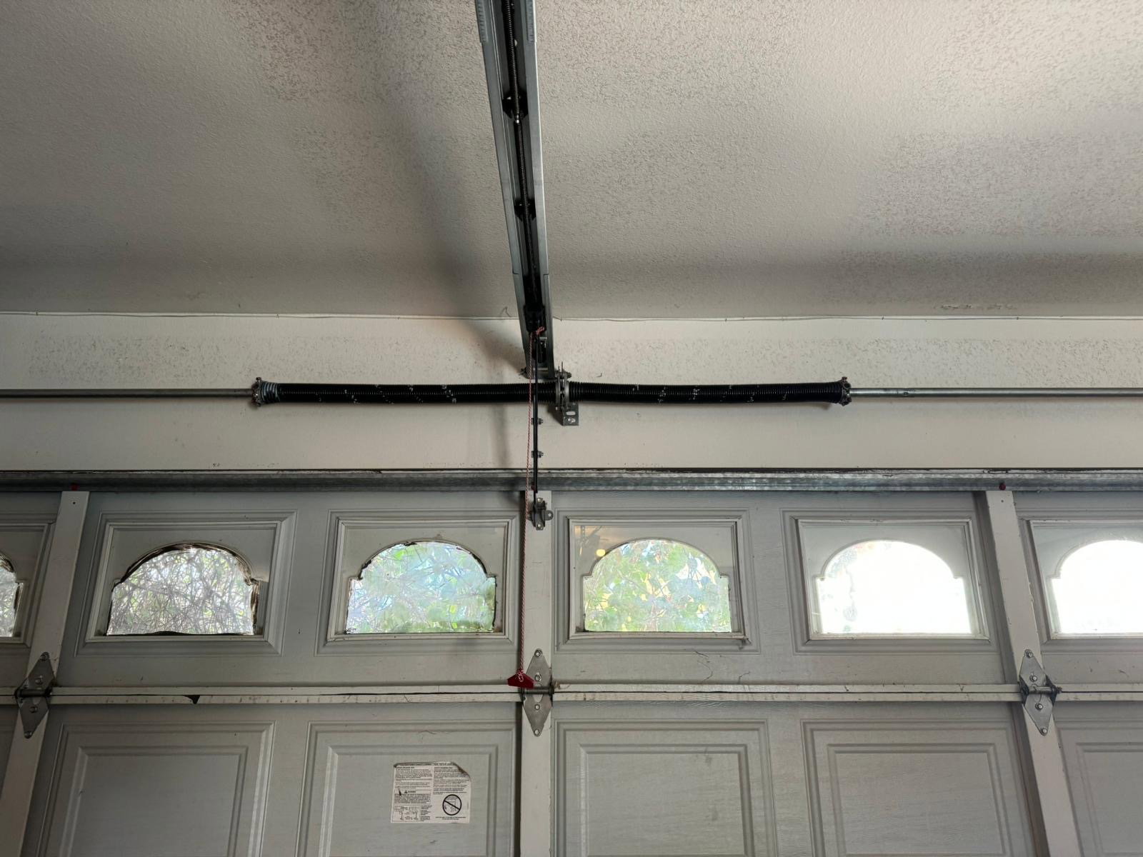 A garage door torsion spring on the shaft above the door, serviced by 24/7 Garage Door and Gate Services in Riverside
